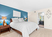 Thumbnail 17 of 40 - a bedroom with a bed and a blue wall and a bathroom at Silver Reef Apartments, Lakewood, Colorado
