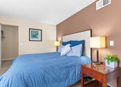 Thumbnail 12 of 40 - a bedroom with a blue bed and a night stand at Silver Reef Apartments, Lakewood, CO, 80228