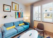 Thumbnail 20 of 65 - A blue couch with yellow pillows sits in a room with a white table and a chair. at Centre Pointe Apartments, Florida