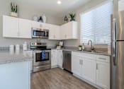 Thumbnail 1 of 15 - A kitchen with white cabinets and stainless steel appliances. at Vistoria At Marley Park Apartments, Arizona, 85379