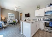 Thumbnail 2 of 15 - A modern kitchen with white appliances and a dining area with a couch and chairs. at Vistoria At Marley Park Apartments, Surprise, 85379