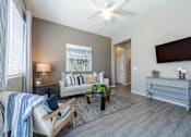 Thumbnail 3 of 15 - A living room with a couch, a chair, a coffee table, and a flat-screen TV mounted on the wall at Vistoria At Marley Park Apartments, Surprise, AZ, 85379