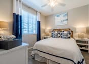 Thumbnail 5 of 15 - A bedroom with a bed, nightstand, and window with curtains. at Vistoria At Marley Park Apartments, Surprise, AZ, 85379