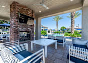 Thumbnail 15 of 15 - A patio with a brick fireplace and striped couches at Vistoria At Marley Park Apartments, Surprise, AZ, 85379