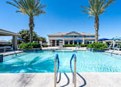 Thumbnail 13 of 15 - A swimming pool surrounded by palm trees and a building in the background at Vistoria At Marley Park Apartments, Arizona, 85379
