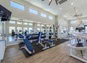 Thumbnail 11 of 15 - A spacious gym with a variety of equipment and a television mounted on the wall at Vistoria At Marley Park Apartments, Arizona