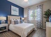 Thumbnail 4 of 15 - A bedroom with a bed, nightstand, and a painting on the wall. at Vistoria At Stadium Apartments, Glendale, AZ, 85305
