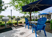 Thumbnail 14 of 15 - A blue chair is in front of a table with a blue umbrella. at Vistoria At Stadium Apartments, Glendale, AZ, 85305