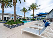 Thumbnail 12 of 15 - A poolside area with sun loungers and palm trees. at Vistoria At Stadium Apartments, Glendale