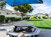 Thumbnail 15 of 15 - A picnic table with a blue umbrella is set up on a concrete slab. at Vistoria At Country Place Apartments, Arizona