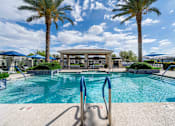 Thumbnail 12 of 15 - A pool surrounded by palm trees and a pavilion. at Vistoria At Country Place Apartments, Tolleson
