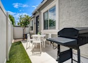 Thumbnail 9 of 15 - A patio with a table, chairs, and a grill.