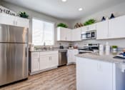 Thumbnail 1 of 15 - A kitchen with white cabinets and a stainless steel refrigerator.