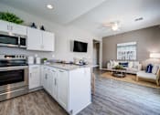 Thumbnail 3 of 15 - A modern kitchen with white cabinets and stainless steel appliances.