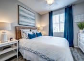 Thumbnail 2 of 3 - Bedroom with blue accent pillows and curtains at Vistoria On Camelback Apartments, Arizona, 85340