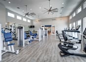 Thumbnail 12 of 15 - A spacious gym with a variety of equipment and a ceiling fan.