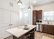 Thumbnail 3 of 46 - a kitchen with a white island and wooden cabinets at Artesia at Lakewood Ranch Apartments, Florida