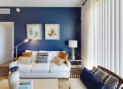 Thumbnail 7 of 35 - a living room with a blue accent wall and a white couch at The Lotus at Village Walk, Fort Myers, FL