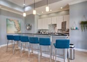 Thumbnail 15 of 26 - a kitchen with a bar and stools in front of it at Magnolia Village Apartments, Jacksonville
