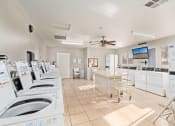 Thumbnail 15 of 26 - a laundry room with washing machines and a counter with chairs