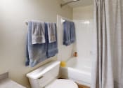 Thumbnail 10 of 27 - a bathroom with a white toilet next to a bathtub with a shower curtain