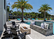 Thumbnail 29 of 36 - a swimming pool with chairs and a fire pit at The Addison on Long Bayou Apartments, Florida