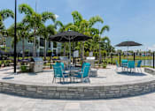 Thumbnail 30 of 36 - a patio with tables and chairs and umbrellas at The Addison on Long Bayou Apartments, Seminole, FL