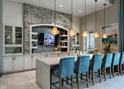 Thumbnail 17 of 36 - a kitchen with a bar and blue chairs at The Addison on Long Bayou Apartments, Seminole, FL, 33772