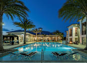 Thumbnail 10 of 36 - a large swimming pool in front of a hotel at night at The Addison on Long Bayou Apartments, Seminole, FL