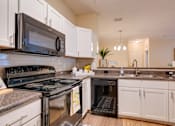 Thumbnail 1 of 26 - a kitchen with white cabinets and black appliances at Magnolia Village Apartments, Jacksonville