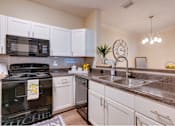 Thumbnail 2 of 26 - a kitchen with white cabinets and black appliances at Magnolia Village Apartments, Jacksonville