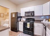 Thumbnail 3 of 26 - a kitchen with white cabinets and black appliances at Magnolia Village Apartments, Florida 32207