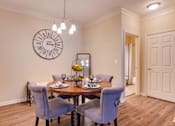 Thumbnail 5 of 26 - a dining room with a table and chairs and a clock on the wall at Magnolia Village Apartments, Florida 32207