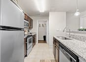 Thumbnail 2 of 40 - a kitchen with white granite countertops and stainless steel appliances
