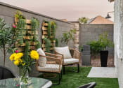 Thumbnail 10 of 33 - a backyard patio with two chairs and a table and a vase of flowers at Onyx at Westgate Apartments, Glendale, AZ