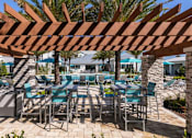 Thumbnail 20 of 51 - a covered patio with tables and chairs and a pool at Enclave at 3230 Apartments, South Daytona, 32119