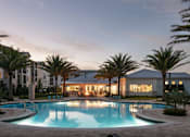 Thumbnail 24 of 51 - A swimming pool in front of a building with palm trees at Enclave at 3230 Apartments, South Daytona, Florida