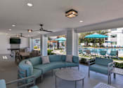 Thumbnail 29 of 51 - A patio with a blue couch and a table at Enclave at 3230 Apartments, South Daytona, FL