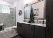 Thumbnail 14 of 51 - A bathroom with a toilet, sink, and mirror at Enclave at 3230 Apartments, South Daytona, 32119