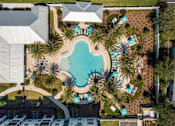 Thumbnail 26 of 51 - a swimming pool with palm trees in front of a hotel at Enclave at 3230 Apartments, South Daytona