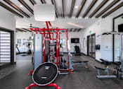 Thumbnail 43 of 51 - A gym with a red weight bench and a black weight plate on the floor at Enclave at 3230 Apartments, South Daytona, FL, 32119