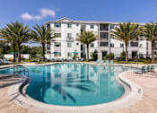 Thumbnail 16 of 51 - a large swimming pool with an apartment building in the background at Enclave at 3230 Apartments, South Daytona, Florida