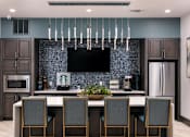 Thumbnail 35 of 51 - A modern kitchen with a dark blue backsplash and a large island with four chairs at Enclave at 3230 Apartments, Florida