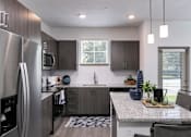 Thumbnail 6 of 51 - A modern kitchen with a stainless steel refrigerator and dark wood cabinets at Enclave at 3230 Apartments, South Daytona