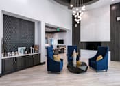 Thumbnail 37 of 51 - A living room with a blue chair and a black coffee table at Enclave at 3230 Apartments, South Daytona
