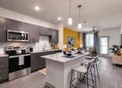Thumbnail 1 of 51 - A modern kitchen with a breakfast bar and a dining area at Enclave at 3230 Apartments, Florida, 32119