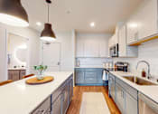 Thumbnail 11 of 54 - A kitchen with a white countertop and blue cabinets. at The Arlow on Kellog, Minnesota
