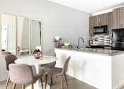 Thumbnail 4 of 19 - A kitchen with a white counter and brown chairs.