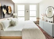 Thumbnail 8 of 19 - A bedroom with a large bed and a mirror on the wall.