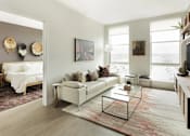 Thumbnail 5 of 19 - A living room with a white couch and a glass coffee table.